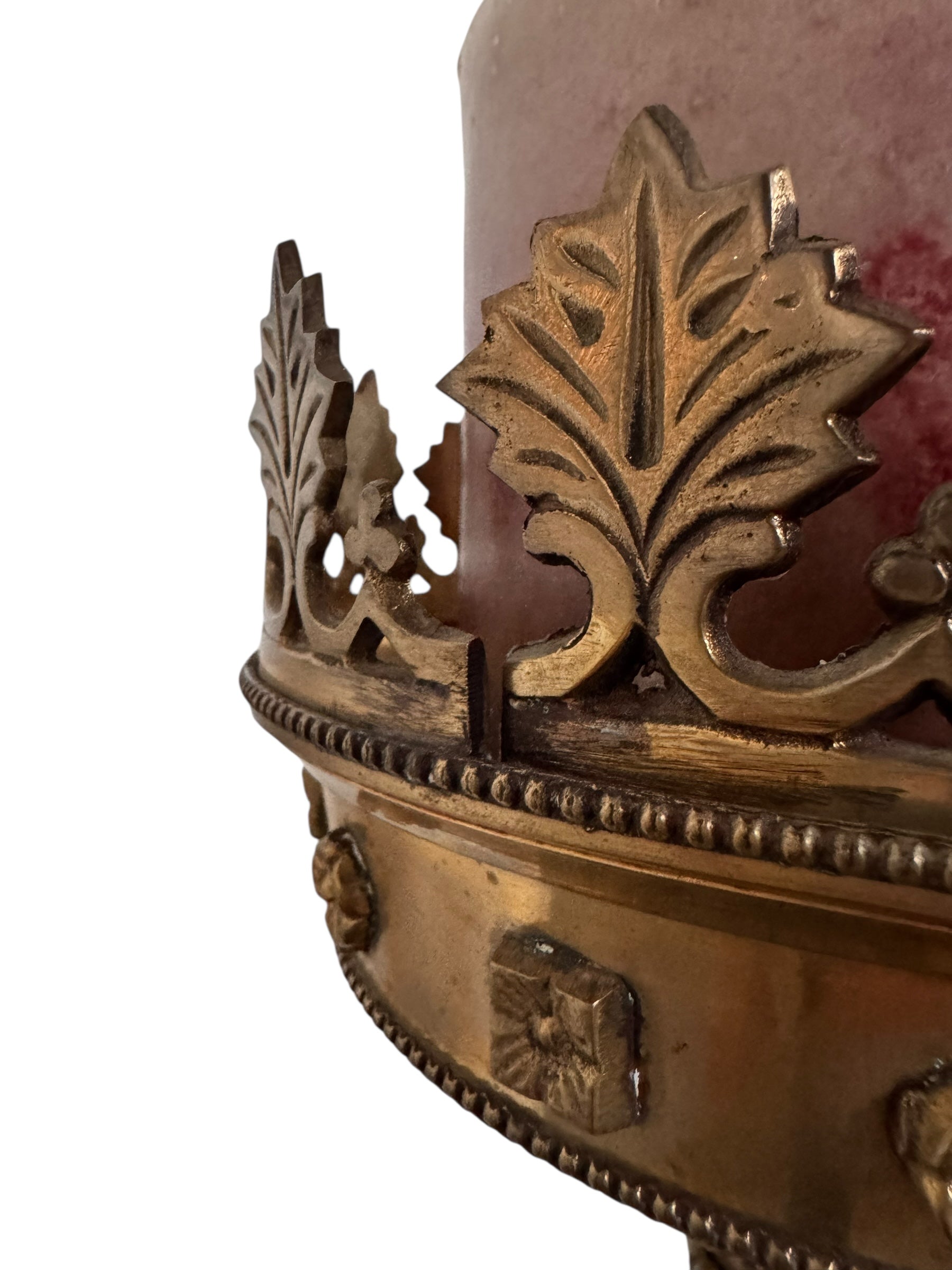 A tall, ornate, antique brass or bronze Gothic church candlestick holder with a pink candle in the top.