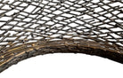 A round metal wall sculpture by Michael Aram, viewed from the front against a stark white background. The piece is composed of a dense, intricate lattice of fine, dark metal wire or twigs woven together to create a textured, web-like pattern. The structure curves inward like a funnel or a vortex, sloping down toward a clean, circular opening in the exact center, creating a strong sense of depth and dimensionality.