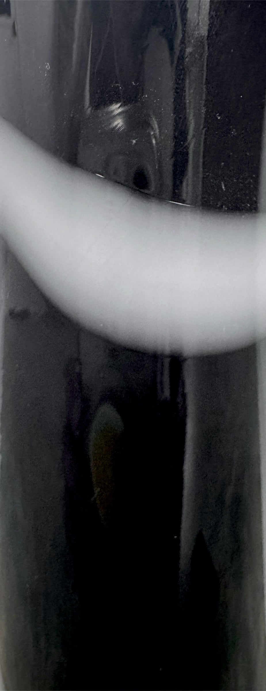 A sleek, hand-blown Polish art glass vase featuring a tall, slender neck that flares into a rounded, bulbous body. The vase is made of opaque black glass decorated with a continuous white spiral ribbon that winds around the entire piece from base to rim. The high-gloss, reflective surface creates sharp highlights, emphasizing its smooth, sculptural silhouette against a plain white background.
