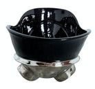 A large, decorative ceramic bowl by Dolbi Cashier in a dramatic Postmodern style. The top half is finished in a polished, piano-black glaze with an organic, wavy "butterfly" rim that dips in the center and rises at the sides. The bottom half is finished in a reflective, metallic silver chrome glaze, featuring bold, geometric-rounded feet and a structured base that appears to "hold" the black vessel. The overall shape is wide and sculptural, reminiscent of 1980s Art Deco Revival.