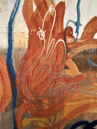 An abstract mixed-media painting on a vertical rectangular panel with a reflective, metallic gold and copper background. The composition features fluid, expressive brushstrokes in warm orange, ochre, and deep blue.
The orange strokes are thick and organic, resembling swirling flames or floral petals, while the blue marks consist of thin, lyrical lines and looped scribbles that dance across the surface. The metallic substrate is visible through the translucent paint, creating a play of light and texture