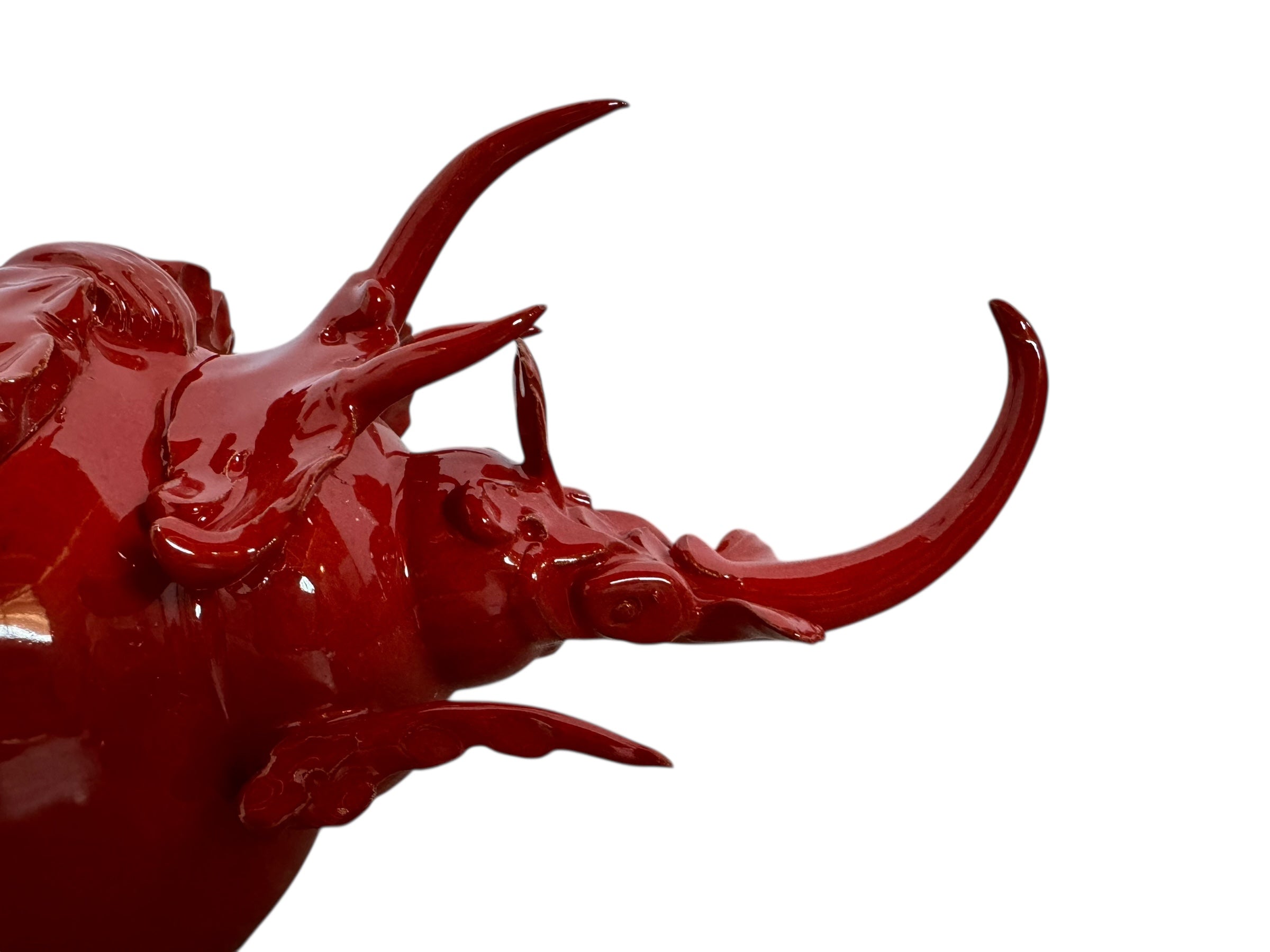 A vibrant, glossy red ceramic sculpture of a rhinoceros beetle by Enza Fasano. The piece features a highly reflective, deep crimson glaze that accentuates its smooth, rounded abdomen and the intricate, jagged textures of its head and horns.
