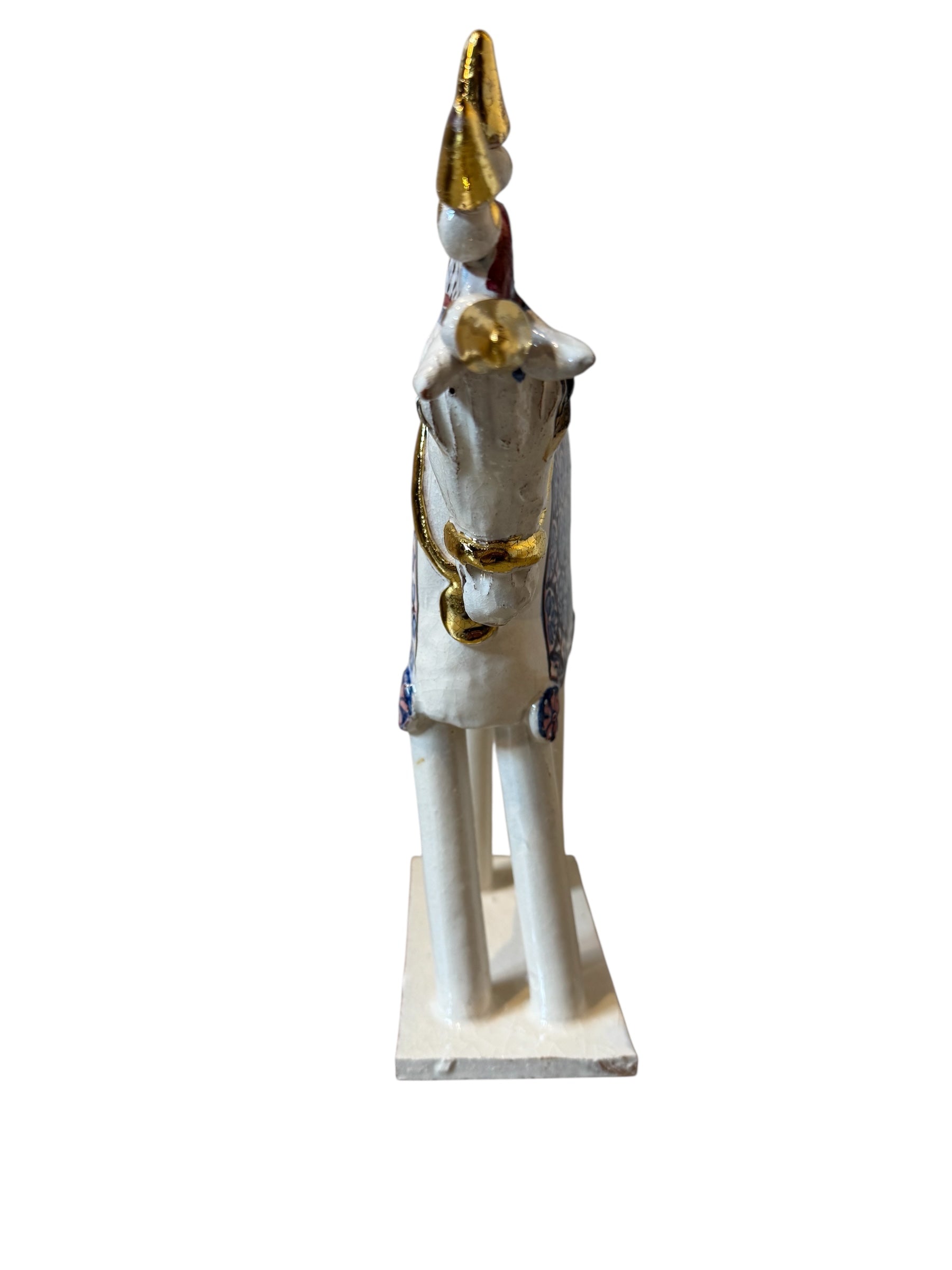 Ceramic horse by Domenico Pinto, featuring a white glazed body, geometric quilting on the saddle, a decorative crown with white and gold accents, and 24Kt gold detailing. The horse stands on four legs and is placed on a white base.