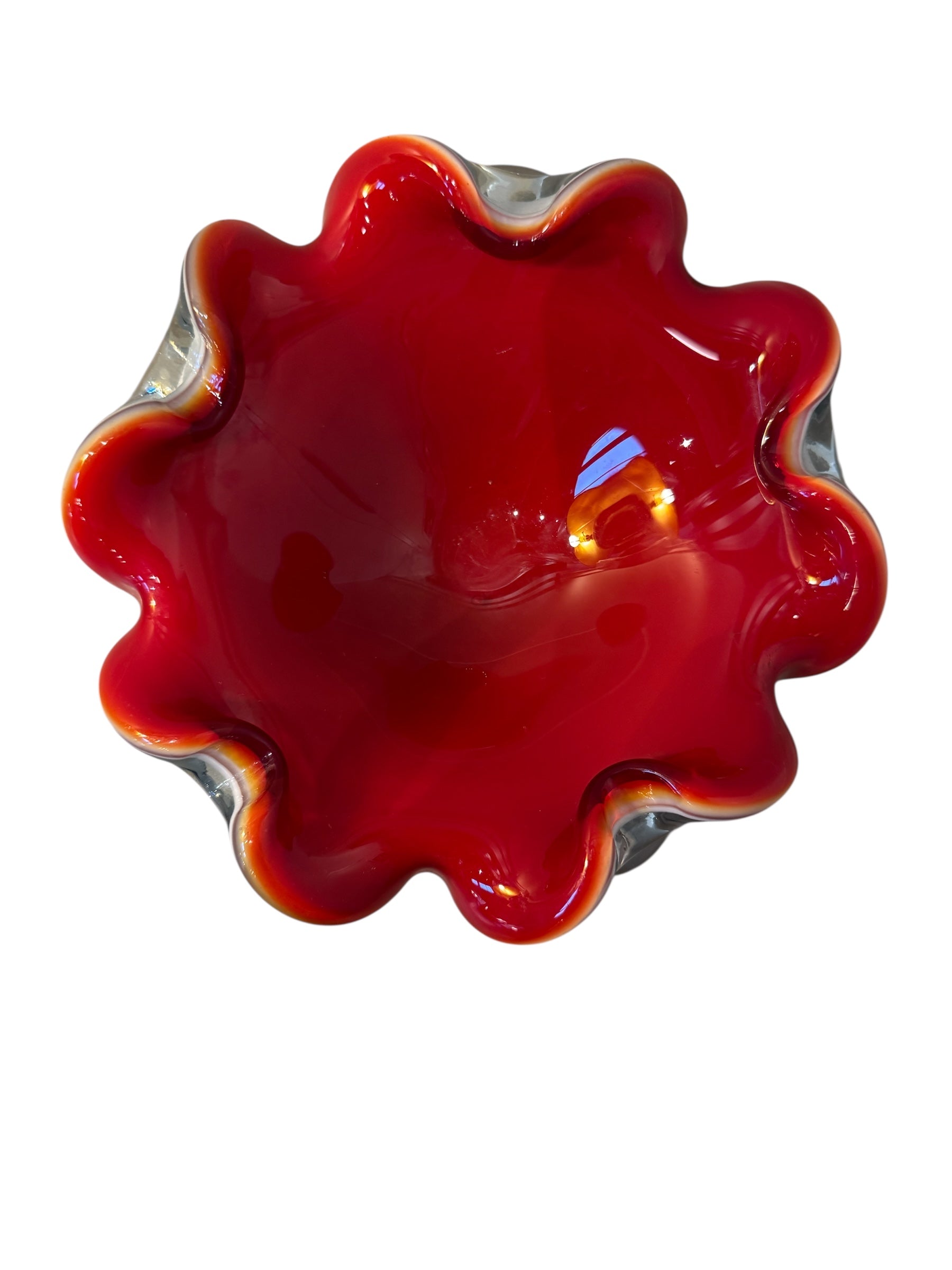 A Murano art glass bowl featuring a vibrant red interior encased in white glass, with a decorative ruffled edge. The piece is handblown, showcasing the Incamiciato technique.