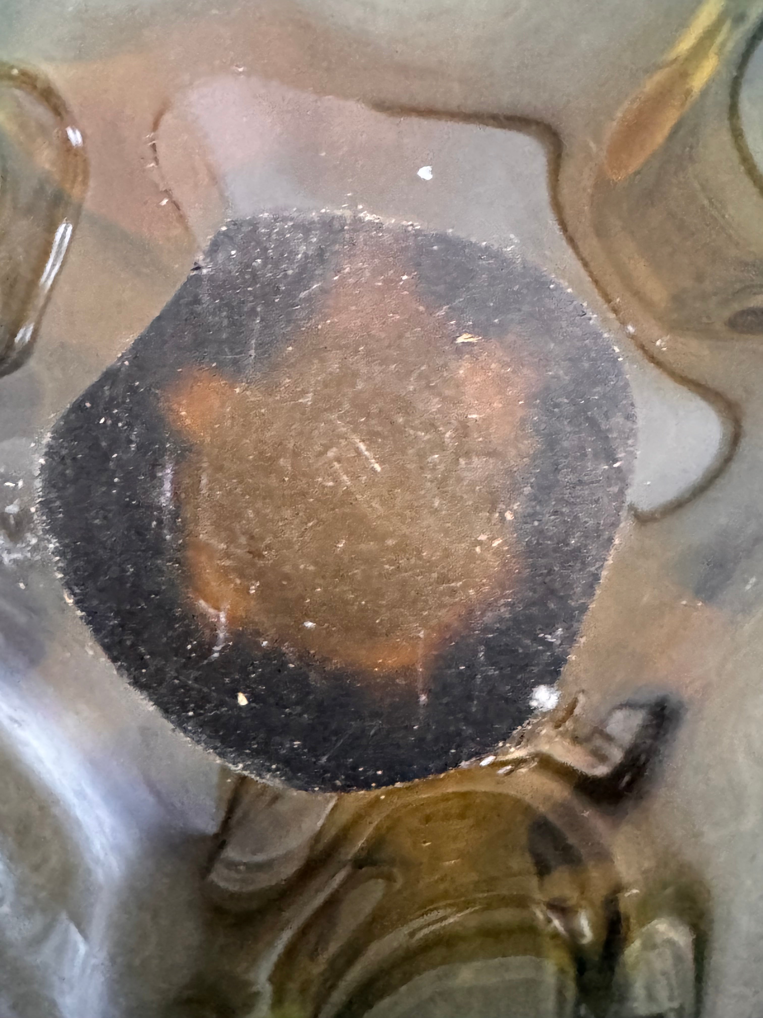 A vintage, hand-blown art glass bowl with a wavy, organic shape and a blue and amber/yellow swirl design