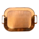 The set includes a large, rectangular, hammered copper tray with geometric openwork handles. Resting on the tray is a tall, slightly tapered copper coffee pot with a wooden handle, a matching smaller creamer pitcher with a similar wooden handle, a lidded sugar bowl, and a tiny matching metal cup or jigger. To the right off the tray sits a large, spherical copper water pitcher or jug with a wide mouth and ice lip.