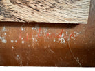 A vertical composition on a bright, reflective metallic background (likely silver or light gold leaf). The piece is defined by sparse, high-energy gestures: a sweeping arc of orange and red at the top, a central cluster of textured red paint, and a scattering of teal-blue "C" shapes and hooks. The metallic surface is highly visible, giving the piece a luminous, modern feel.
