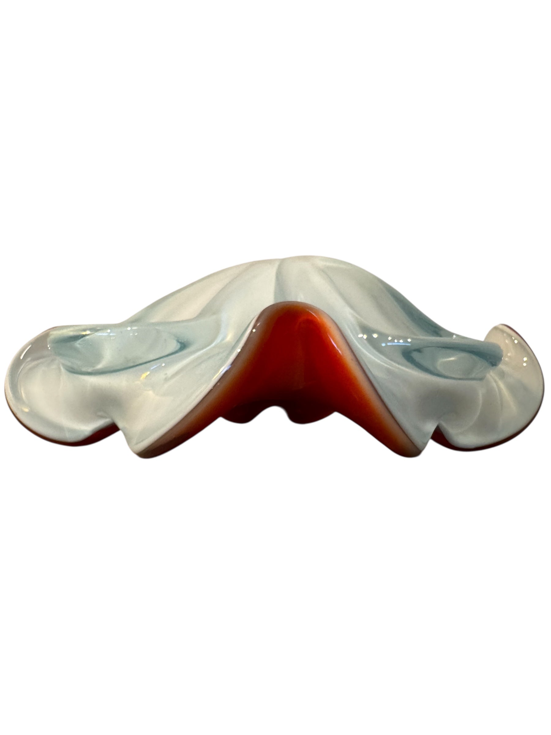 A Murano art glass bowl featuring a vibrant red interior encased in white glass, with a decorative ruffled edge. The piece is handblown, showcasing the Incamiciato technique.