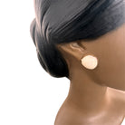 a vintage ceramic bust featuring a woman with brown skin, dark eyes, and orange lips. Her black hair is sleek and parted on the side, pulled back into a low style. She wears a small, round white earring in her right ear lobe. The bust includes her head, neck, and the upper part of her shoulders