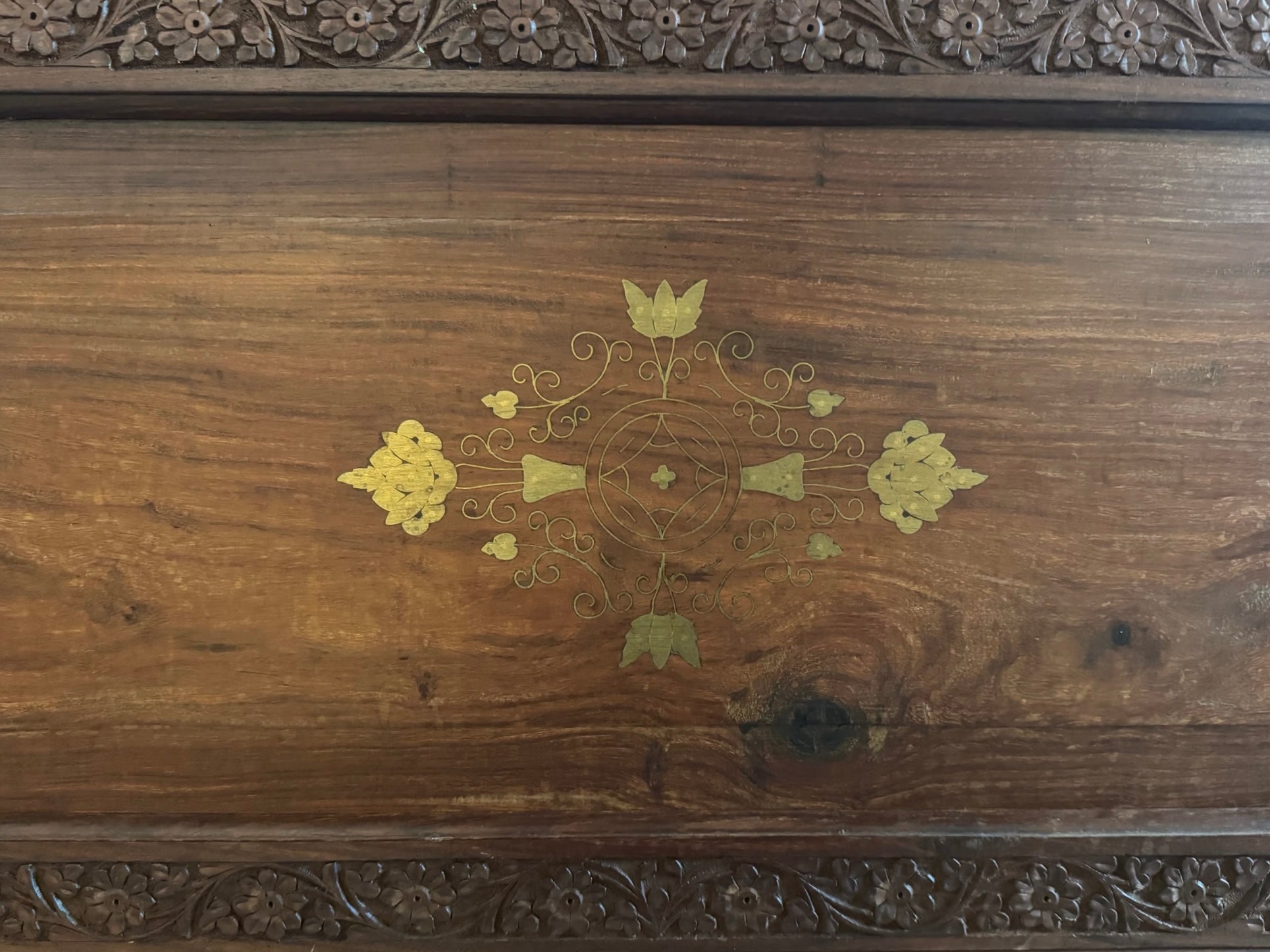 Antique bar cabinet with wood inlay and brass floral details, open to reveal interior shelving and bar storage