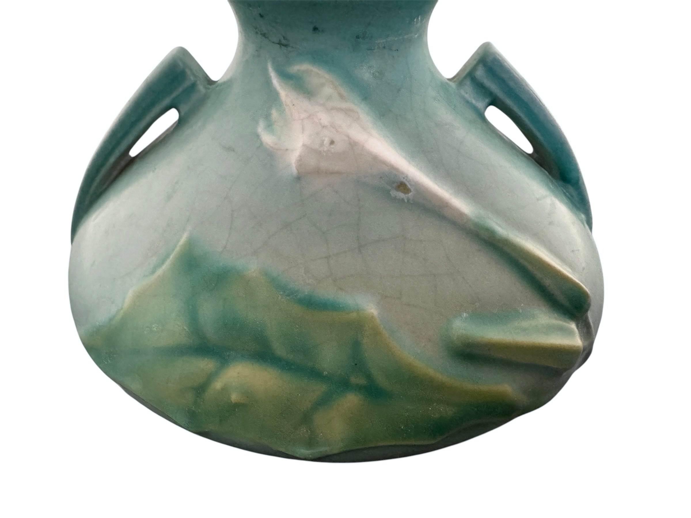 A squat, rounded vintage Roseville pottery vase in a light teal-blue matte glaze. The vase features two small, angular geometric handles on its shoulders and a flared rim. Embossed on the front is a cluster of textured, green and pale-yellow thornapple blossoms tucked against sharp, serrated green leaves. The surface shows a subtle, fine network of age-related crazing lines throughout the glaze.