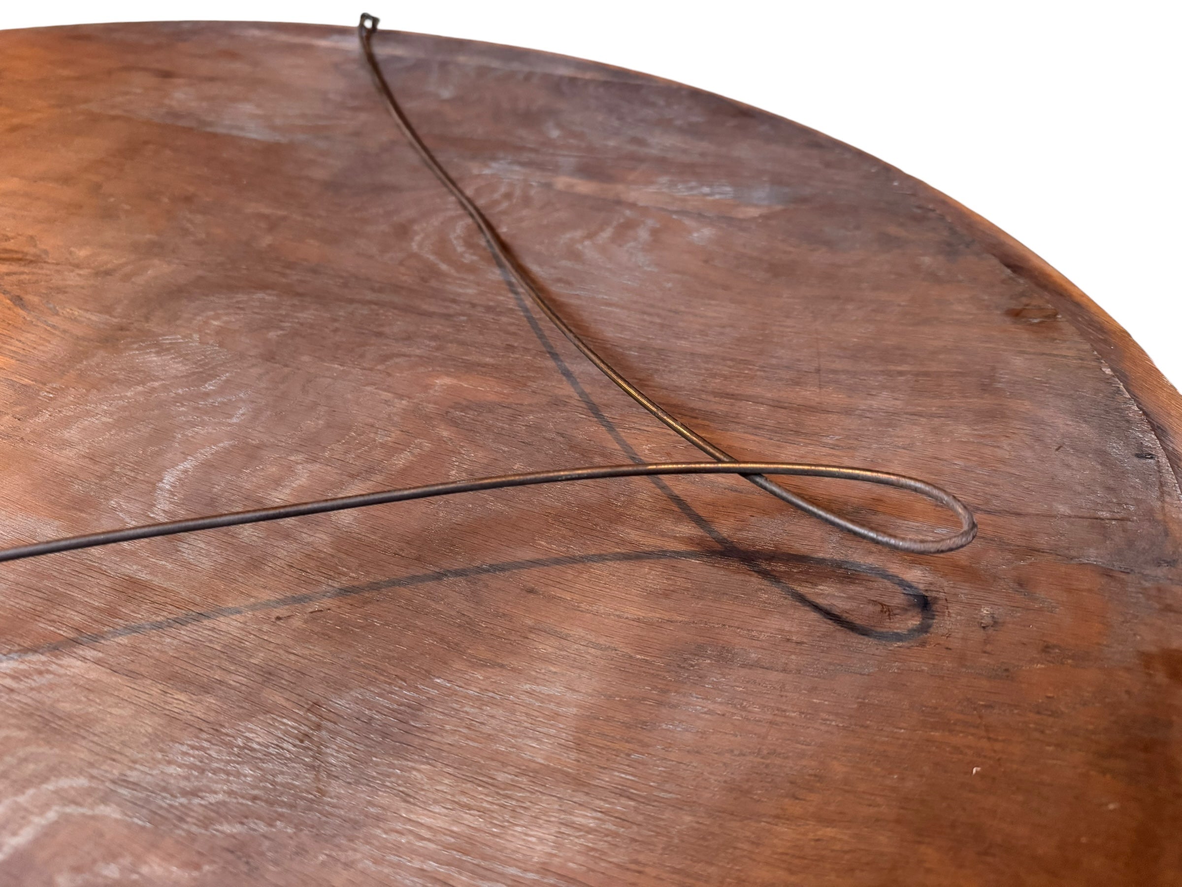 An oval-shaped mirror featuring a wooden frame and an ornate metal crest at the top.