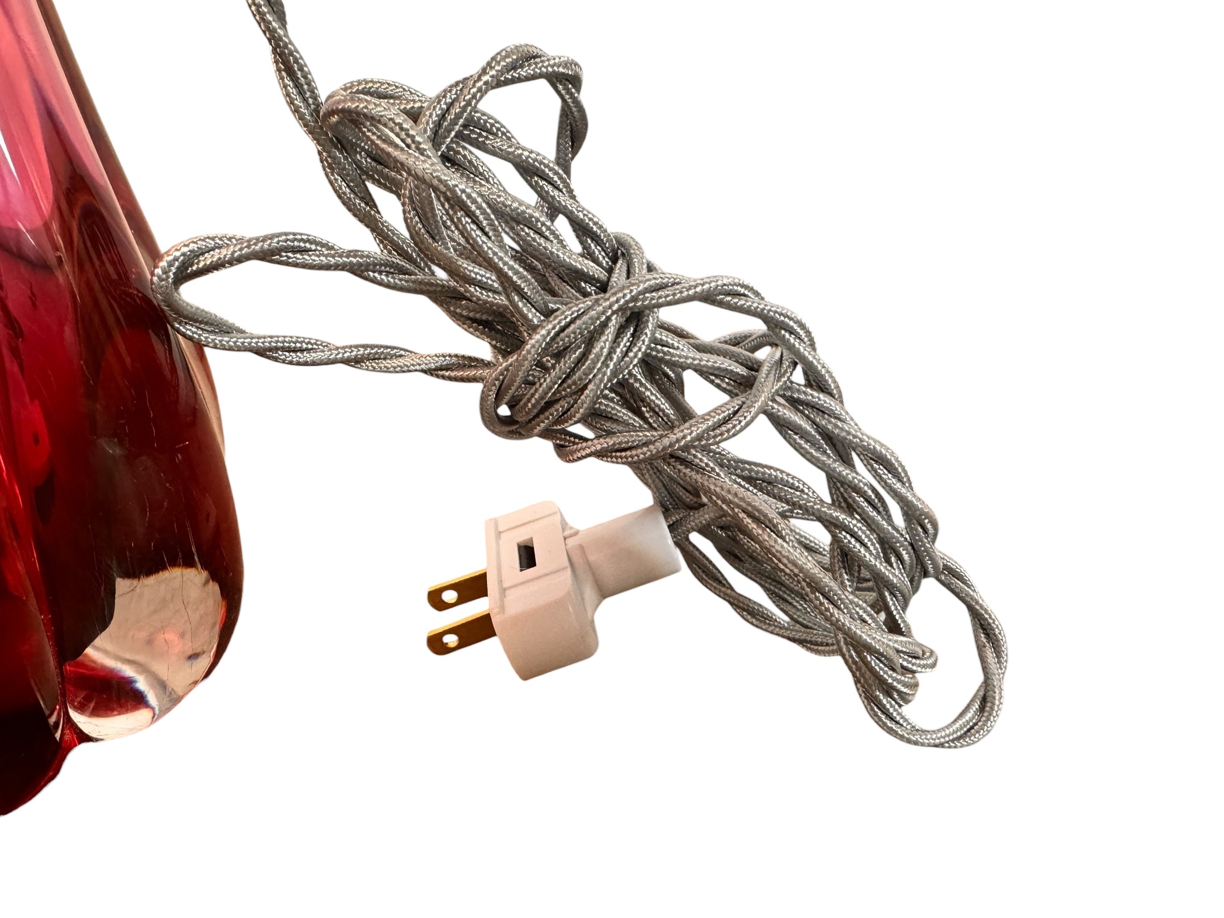 A table lamp featuring a teardrop-shaped, reddish-purple glass base and a conical, pleated, light-pink fabric shade.