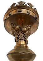 A tall, ornate, antique brass or bronze Gothic church candlestick holder with a pink candle in the top.