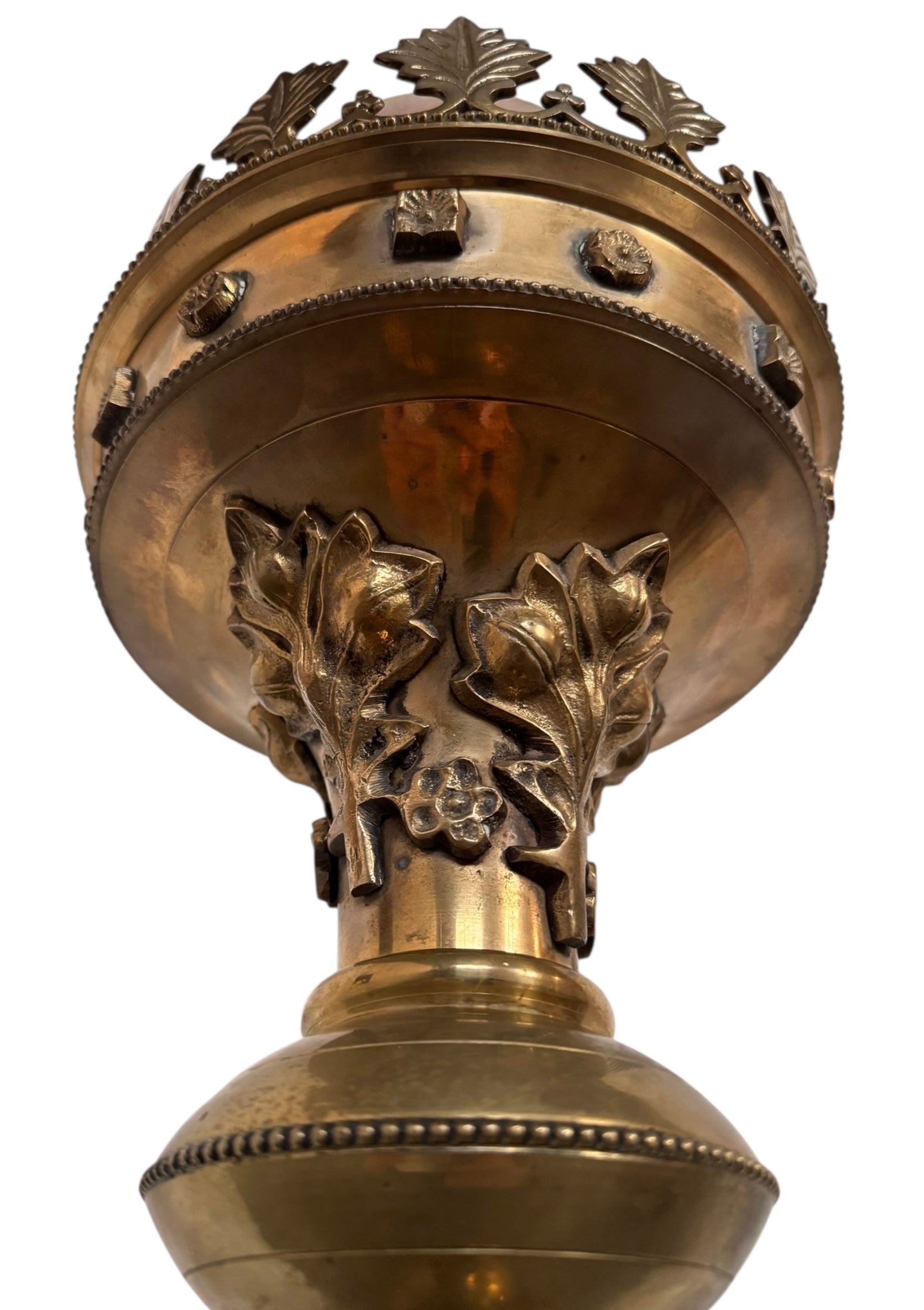 A tall, ornate, antique brass or bronze Gothic church candlestick holder with a pink candle in the top.