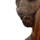 An elegant hand-carved bust of a woman made from rich, polished dark ebony wood with striking reddish-brown grain patterns running vertically through her face and chest. The sculpture features a serene expression with closed eyes, a slender nose, and relaxed lips. Her voluminous, textured hair rises upward in a Fan-like shape, intricately carved with fine lines and adorned with small, delicate flower details. The bust includes her bare shoulders and upper chest, resting on a flat base.
