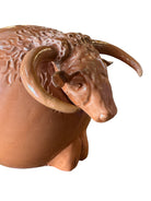 Terracotta colored ceramic Highland cow sculpture with a shaggy coat and curved horns