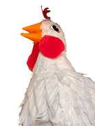 A white chicken pinata with red comb and wattles, and orange beak and legs, standing upright.