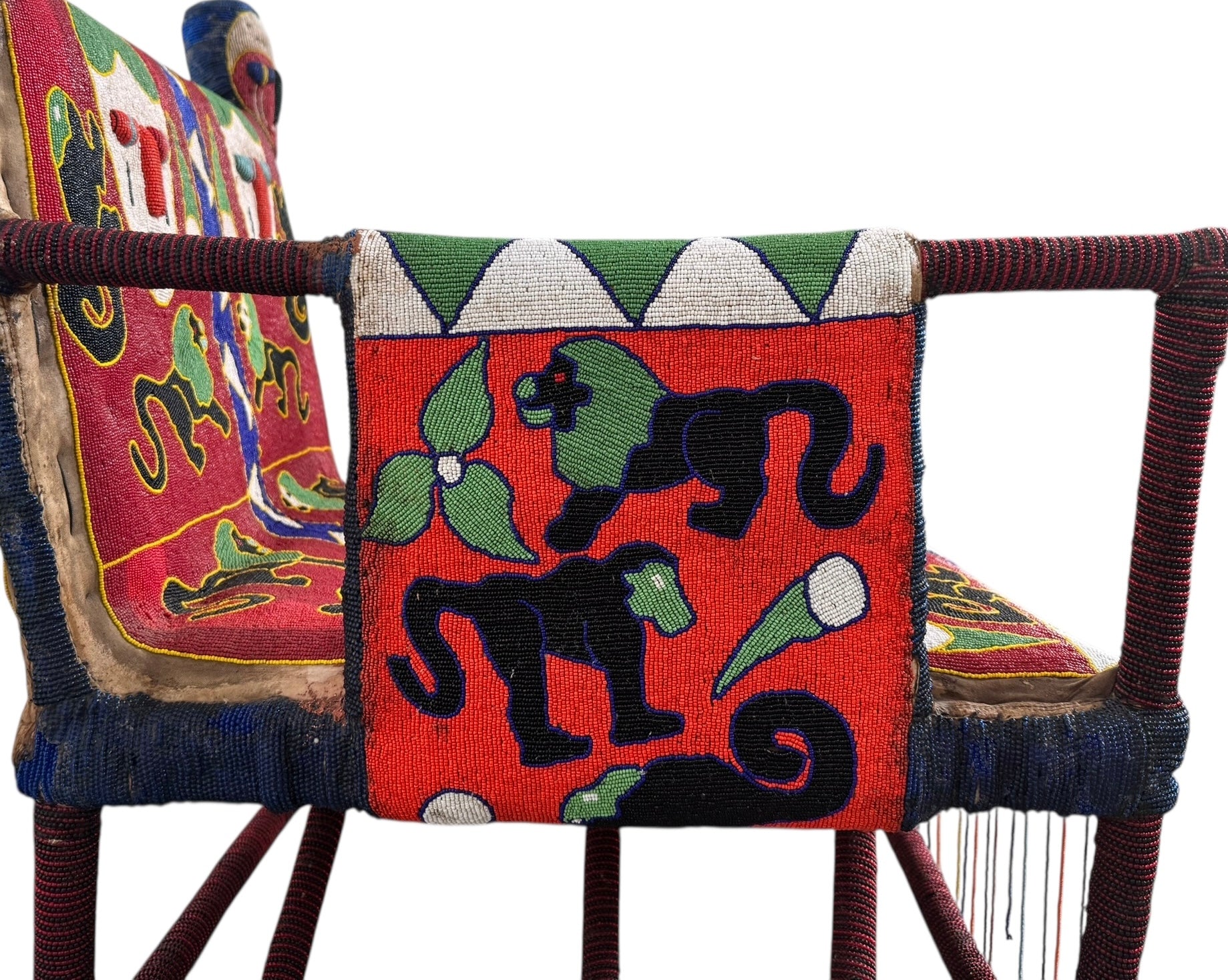 Close-up of a Yoruba beaded armchair, featuring vibrant red, blue, and green beads in a pattern of stylized masks and animals such as lions and zebras