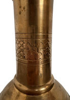 A tall, ornate, antique brass or bronze Gothic church candlestick holder with a pink candle in the top.