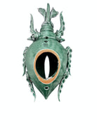 A ceramic sculpture of a stylized beetle by Enza Fasano, featuring a deep emerald green glaze with dark, metallic bronze-colored accents. The beetle is depicted with a highly textured, ribbed shell (elytra) and prominent, curved horns. Its legs are stylized with suckers, reminiscent of octopus tentacles. The piece has a glossy finish and rests against a plain white background.