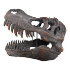 a pair of matching Tyrannosaurus Rex skull sculptures facing inward toward each other against a solid white background. The resin or stone-like replicas are realistically detailed with a weathered, dark gray and brownish-rust finish. Both skulls are sculpted with their jaws wide open, showcasing rows of sharp, pointed teeth with stained orange and brown tips. The skull on the left is angled slightly to the right, and the skull on the right is angled slightly to the left, creating a symmetrical presentation.