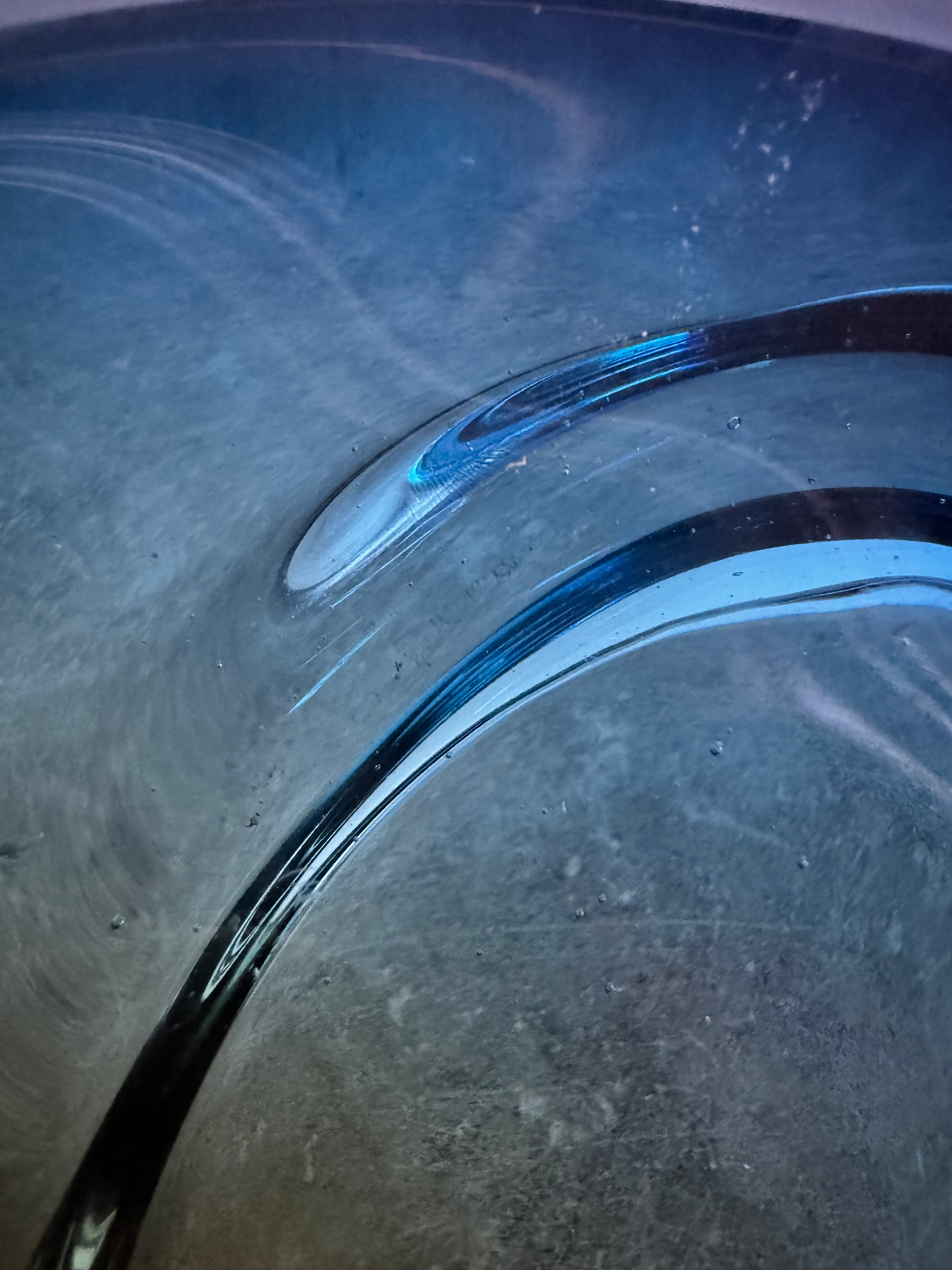 A vintage, hand-blown art glass bowl with a wavy, organic shape and a blue and amber/yellow swirl design