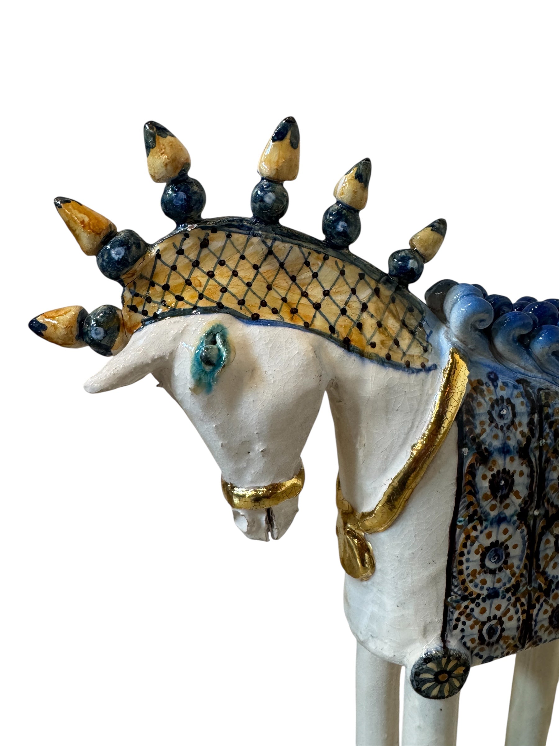 Ceramic horse by Domenico Pinto, featuring a white glazed body, geometric quilting on the saddle, a decorative crown with black and gold accents, and 24Kt gold detailing. The horse stands on four legs and is placed on a white base.