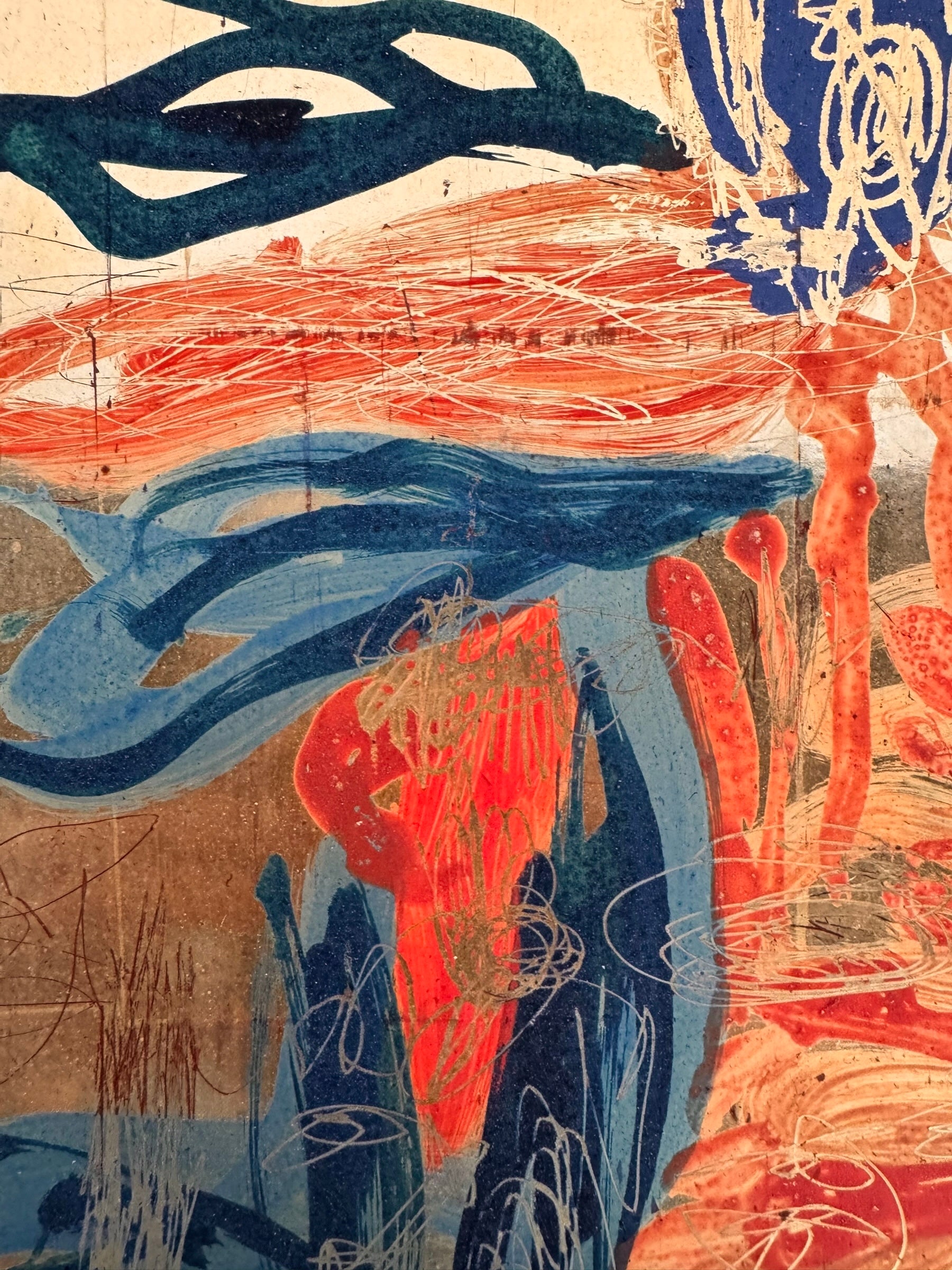 A vertical abstract painting on a shimmering gold-leaf background. The piece is filled with energetic, calligraphic scribbles and fluid shapes in vibrant orange, deep teal, and touches of red. The brushwork varies from thick, opaque strokes to thin, wiry lines that dance across the reflective surface. The composition feels organic and chaotic, like a dense thicket or a fire.
