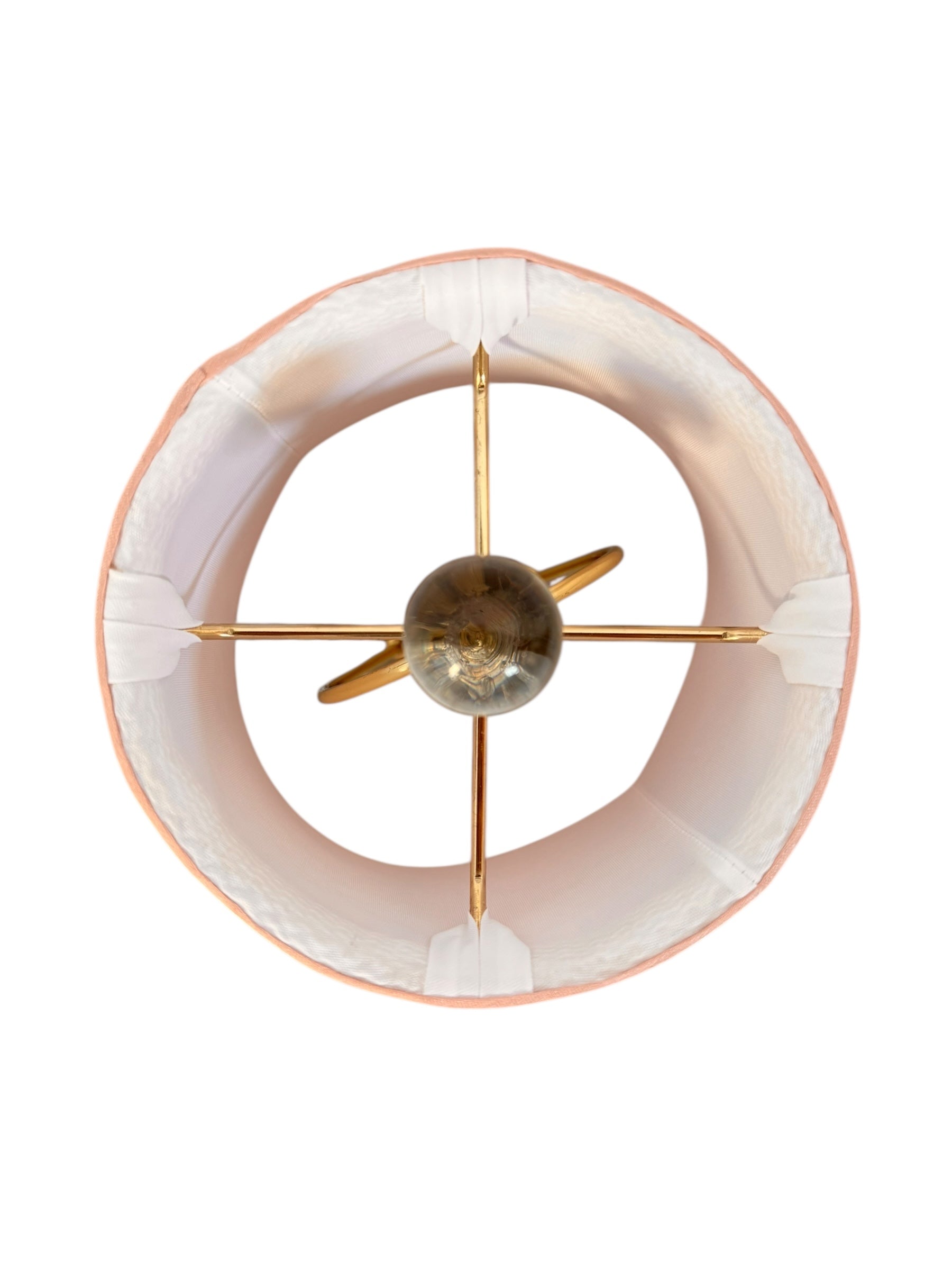 A table lamp featuring a teardrop-shaped, reddish-purple glass base and a conical, pleated, light-pink fabric shade.