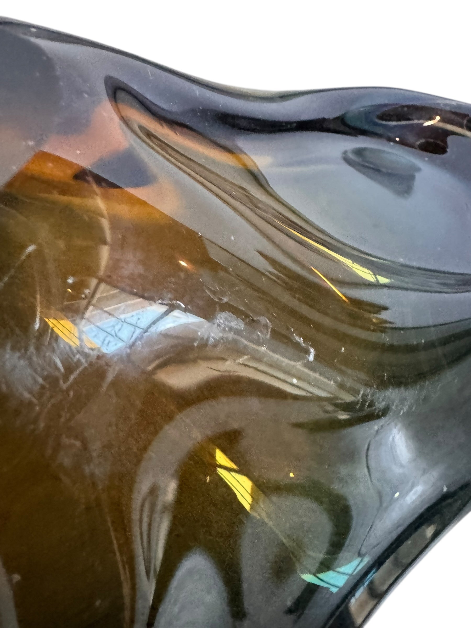 A vintage, hand-blown art glass bowl with a wavy, organic shape and a blue and amber/yellow swirl design