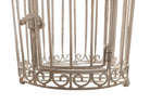 A single, white or cream-colored, decorative wrought iron bird cage with a hinged door and a hanging loop at the top. The cage has a vintage or antique style 