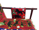 Close-up of a Yoruba beaded armchair, featuring vibrant red, blue, and green beads in a pattern of stylized masks and animals such as lions and zebras