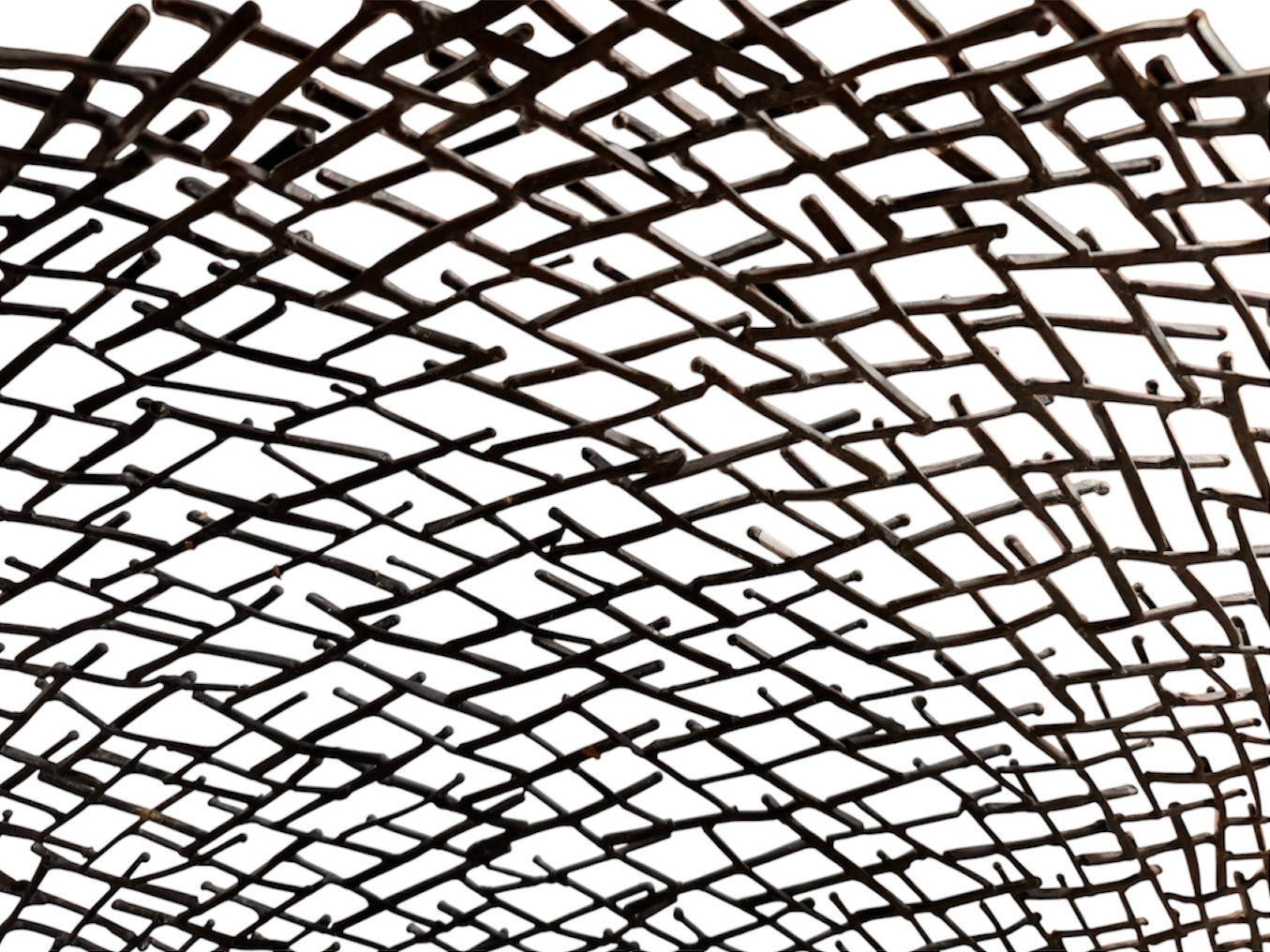 A round metal wall sculpture by Michael Aram, viewed from the front against a stark white background. The piece is composed of a dense, intricate lattice of fine, dark metal wire or twigs woven together to create a textured, web-like pattern. The structure curves inward like a funnel or a vortex, sloping down toward a clean, circular opening in the exact center, creating a strong sense of depth and dimensionality.