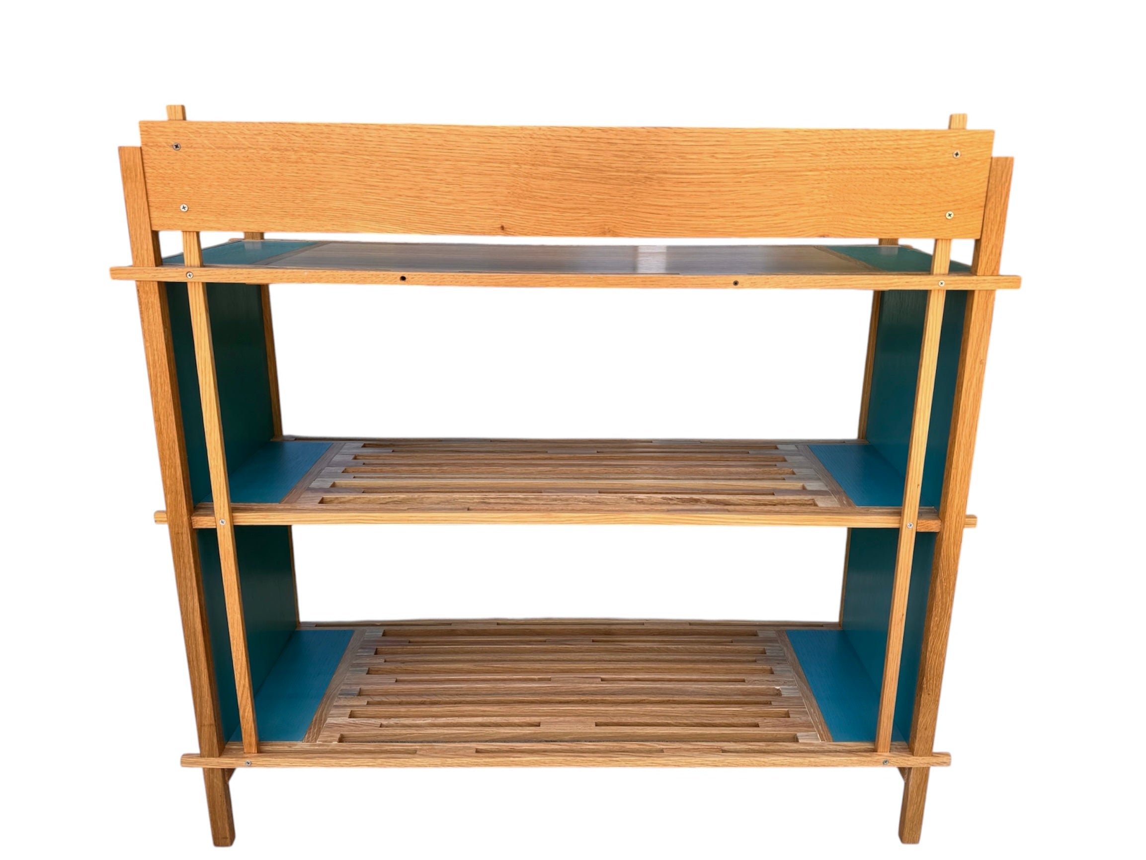 A three-tiered wooden shelving unit featuring a mix of light oak and teal-colored panels. The piece has an open, structural design with visible joinery, vertical supports that extend past the top shelf, and a horizontal backrest at the top. The middle and bottom shelves feature slatted wood center sections flanked by solid teal panels, while the top surface is primarily solid wood with teal accents at the edges.