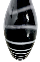 A sleek, hand-blown Polish art glass vase featuring a tall, slender neck that flares into a rounded, bulbous body. The vase is made of opaque black glass decorated with a continuous white spiral ribbon that winds around the entire piece from base to rim. The high-gloss, reflective surface creates sharp highlights, emphasizing its smooth, sculptural silhouette against a plain white background.
