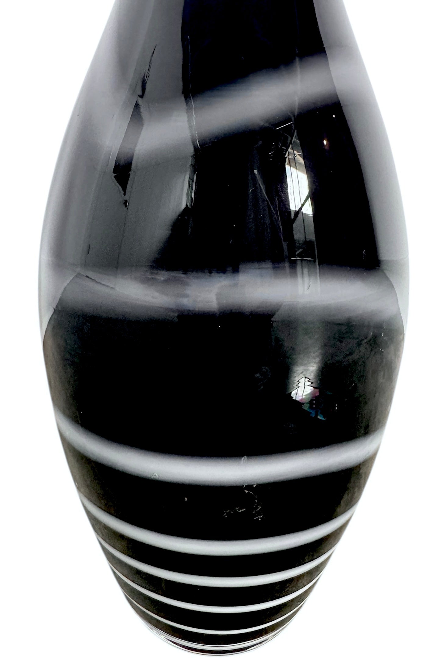 A sleek, hand-blown Polish art glass vase featuring a tall, slender neck that flares into a rounded, bulbous body. The vase is made of opaque black glass decorated with a continuous white spiral ribbon that winds around the entire piece from base to rim. The high-gloss, reflective surface creates sharp highlights, emphasizing its smooth, sculptural silhouette against a plain white background.

