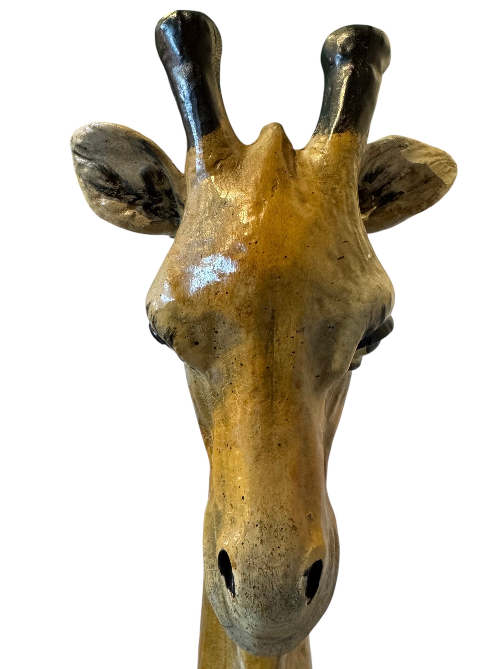 A hand-painted, cast resin sculpture of a seated giraffe. The giraffe has a long neck, is predominantly gold with light markings, and is in a resting pose. The sculpture is against a plain white background