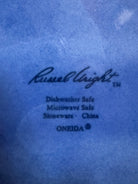 A Russel Wright American Modern stoneware water pitcher in a glossy Manitoga blue glaze is centered against a white background. The pitcher has a teardrop shape, a large handle, and a wide spout