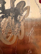 A vertical abstract work on a weathered gold-leaf panel. The upper section features bold, dark red calligraphic symbols resembling distorted kanji or script. Below, delicate, dotted white lines wind through the composition like strings of pearls or constellations. A slender, vertical form in vibrant red stands on the right, while muted, smoky-grey washes of paint ground the bottom of the piece.