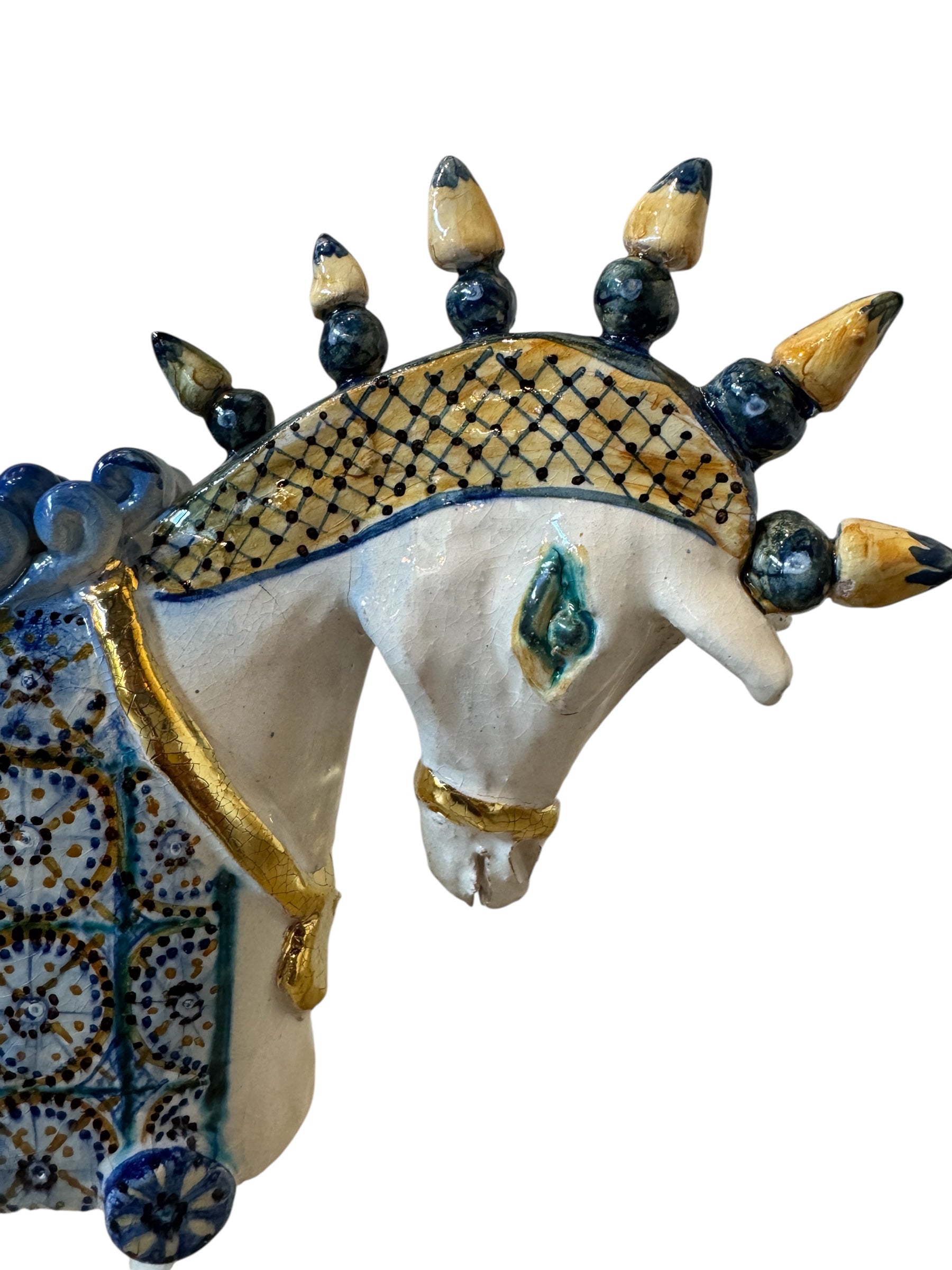 Ceramic horse by Domenico Pinto, featuring a white glazed body, geometric quilting on the saddle, a decorative crown with black and gold accents, and 24Kt gold detailing. The horse stands on four legs and is placed on a white base.
