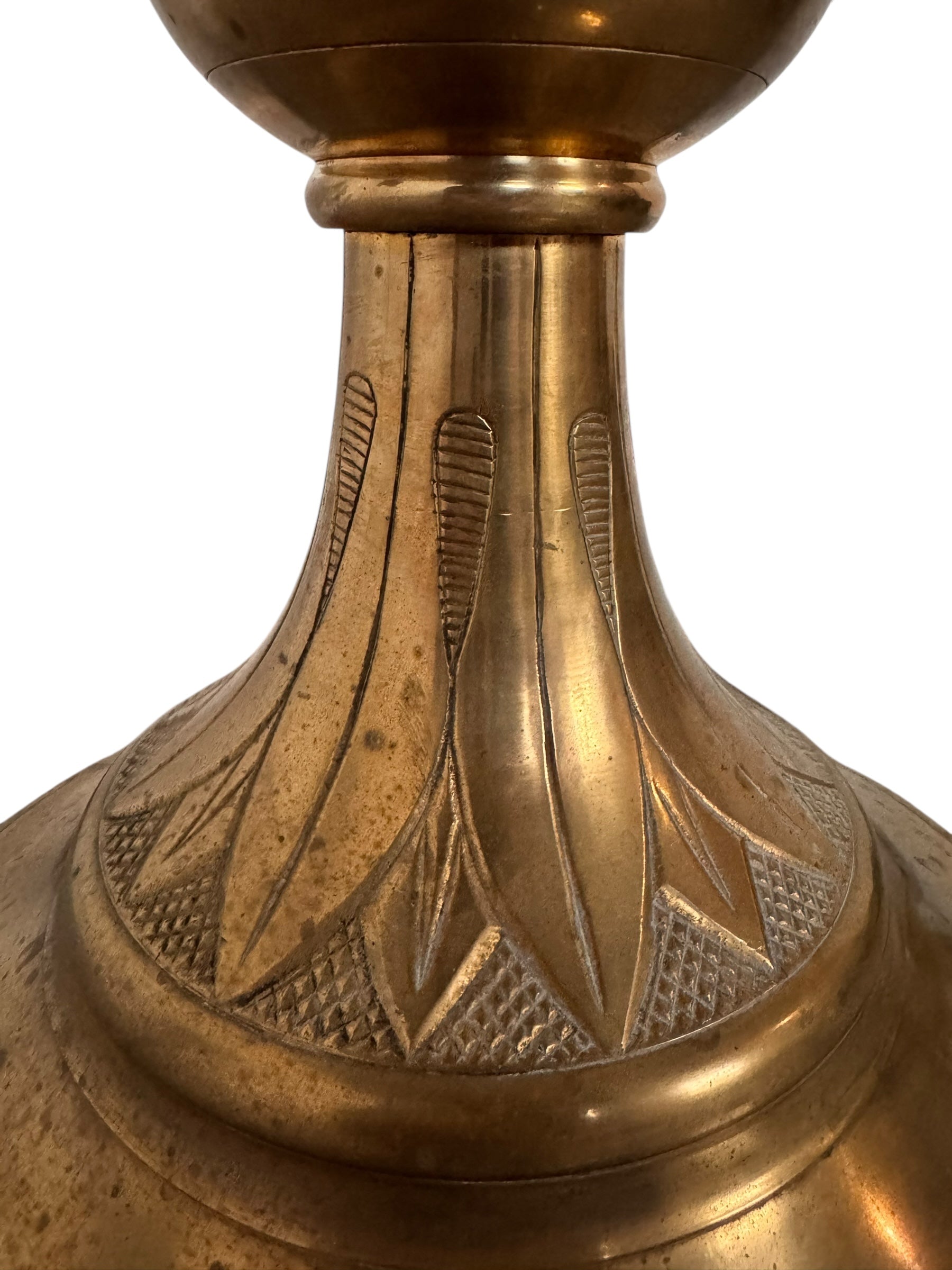 A tall, ornate, antique brass or bronze Gothic church candlestick holder with a pink candle in the top.