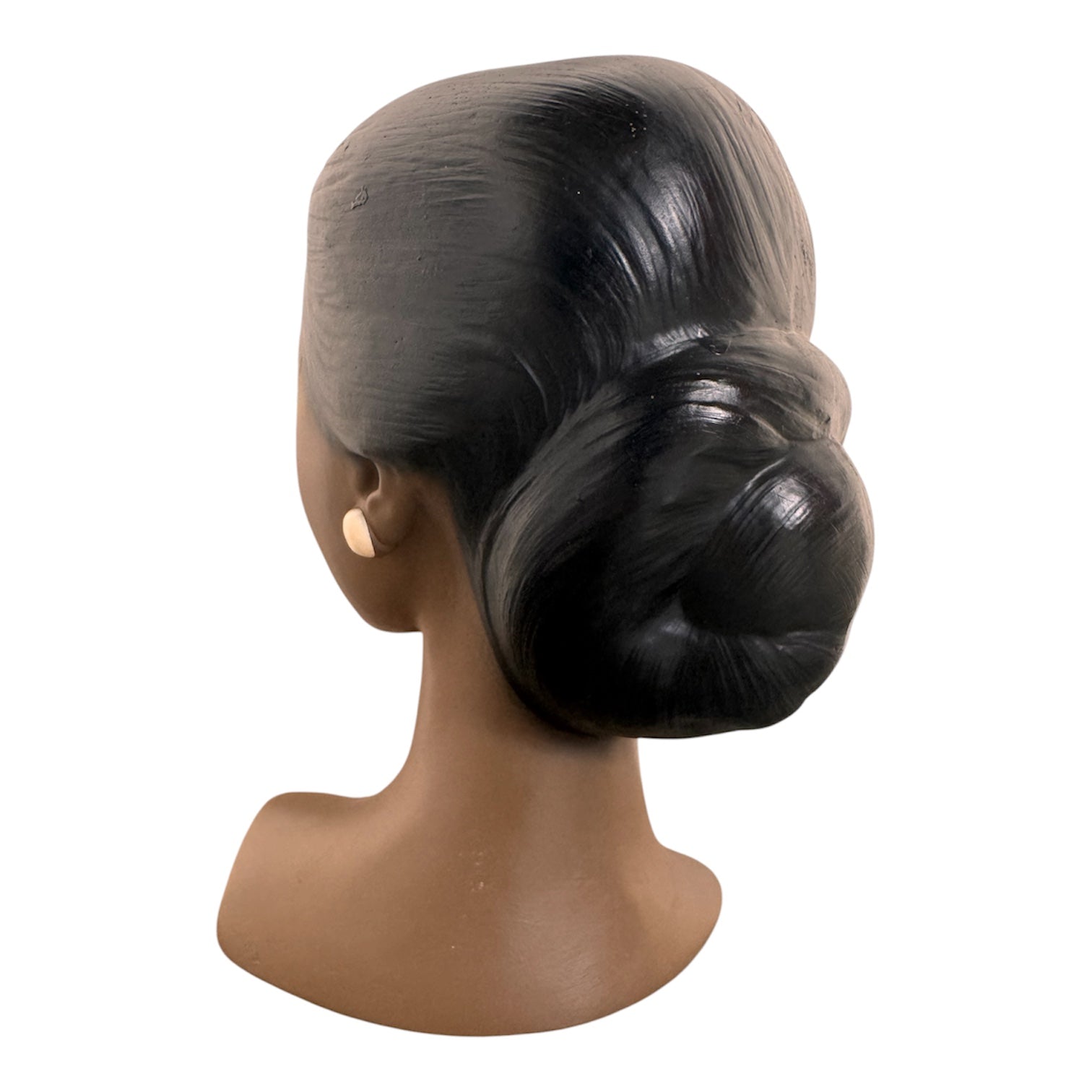 a vintage ceramic bust featuring a woman with brown skin, dark eyes, and orange lips. Her black hair is sleek and parted on the side, pulled back into a low style. She wears a small, round white earring in her right ear lobe. The bust includes her head, neck, and the upper part of her shoulders