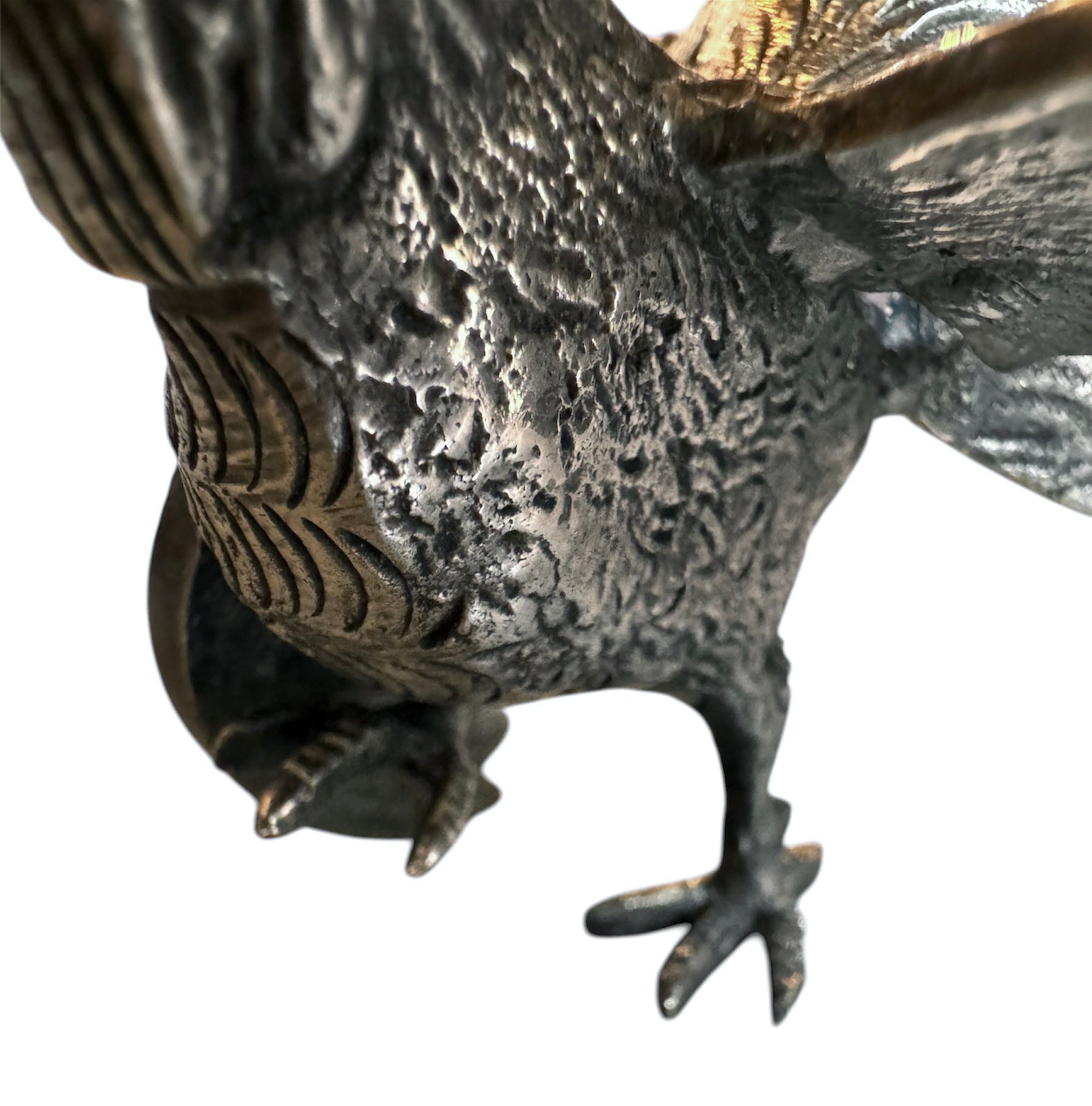 A pair of vintage, silver-plated brass fighting rooster figurines positioned in a confrontational stance against a white background. The rooster on the left is crouched low with its head down and tail feathers fanned high, while the rooster on the right stands more upright with its wings slightly flared. Both feature intricate feather detailing, a metallic patina showing hints of brass through the silver, and small, bright red glass eyes.