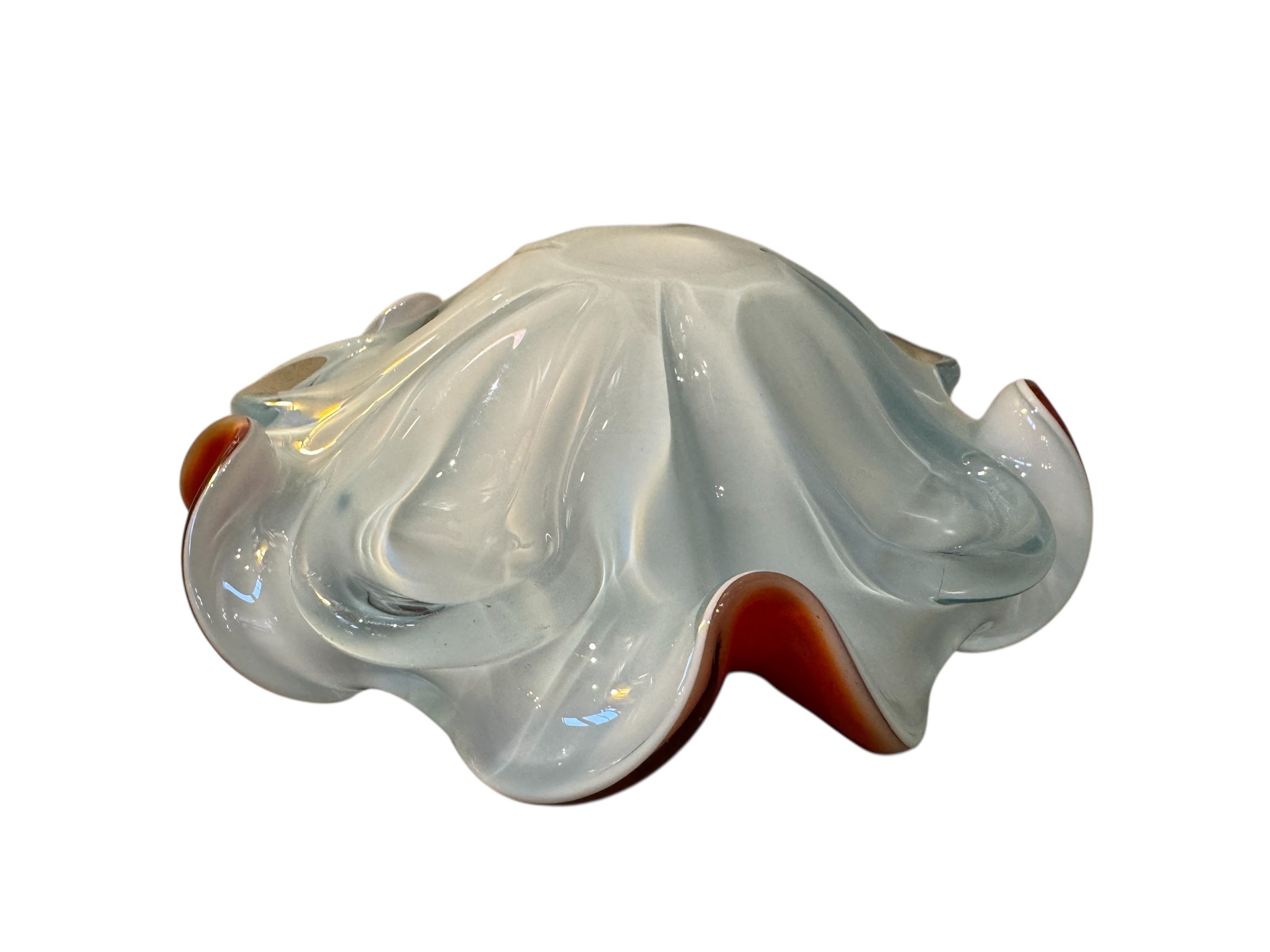 A Murano art glass bowl featuring a vibrant red interior encased in white glass, with a decorative ruffled edge. The piece is handblown, showcasing the Incamiciato technique.