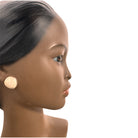 a vintage ceramic bust featuring a woman with brown skin, dark eyes, and orange lips. Her black hair is sleek and parted on the side, pulled back into a low style. She wears a small, round white earring in her right ear lobe. The bust includes her head, neck, and the upper part of her shoulders