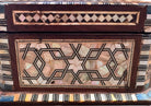 An ornate octagonal Syrian inlaid box, intricately decorated with geometric patterns made from dark wood, iridescent mother-of-pearl, vibrant abalone shell, and pale bone