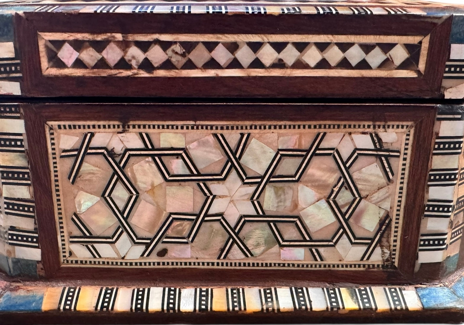 An ornate octagonal Syrian inlaid box, intricately decorated with geometric patterns made from dark wood, iridescent mother-of-pearl, vibrant abalone shell, and pale bone