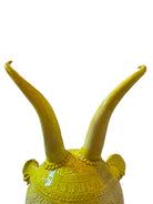 Yellow ceramic sculpture titled 'The Ram Oracle' by Enza Fasano, featuring a round body with intricate, hand-incised patterns and long, stylized ram-like horns
