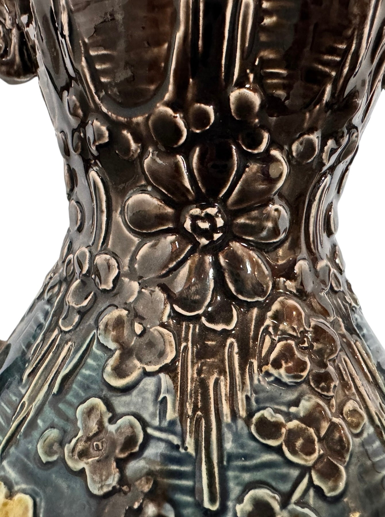 An ornate, dark glazed ceramic Art Nouveau vase with two handles and raised floral designs in yellow, purple, and green.